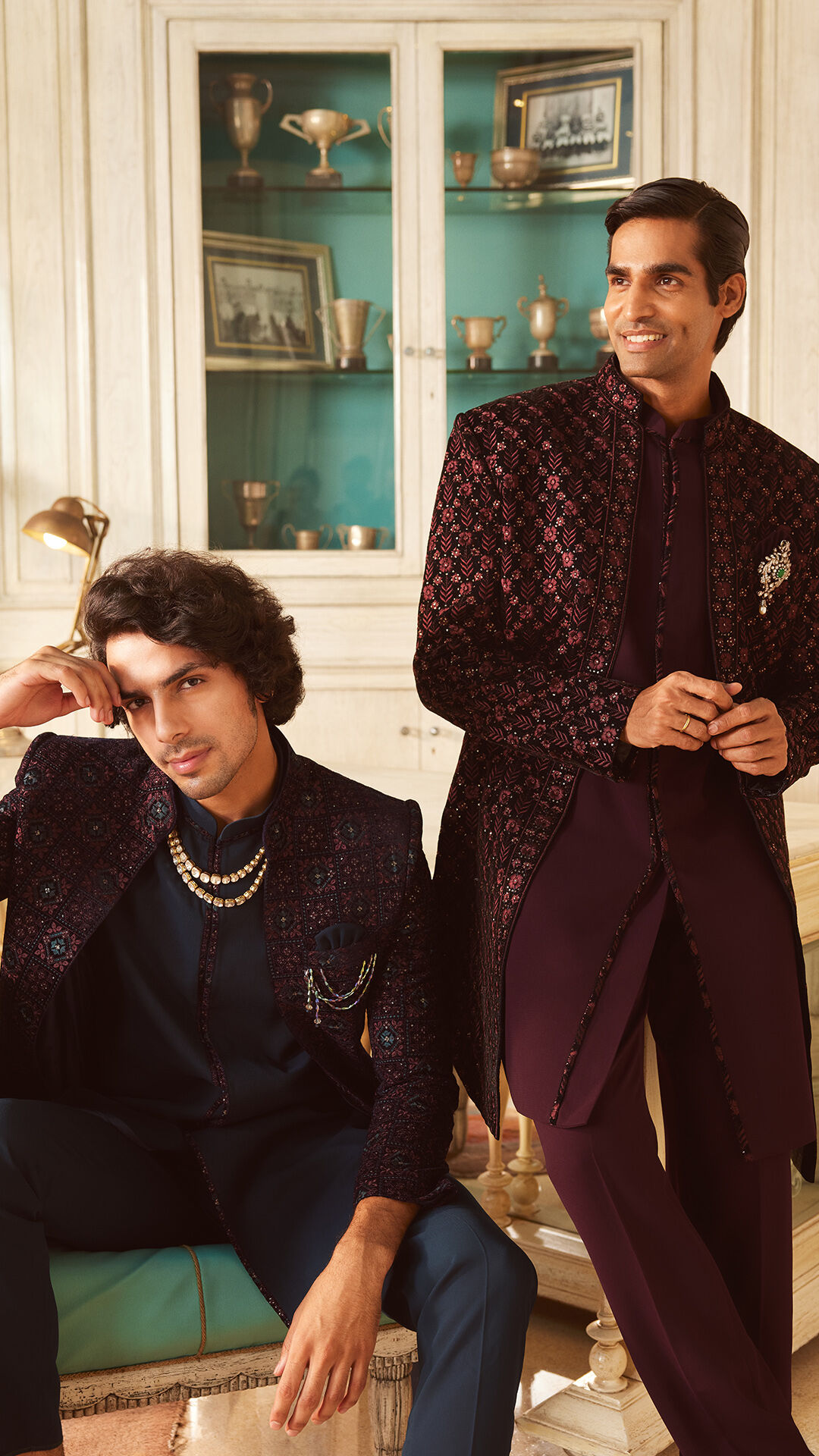 Stylish groomsmen in designer embroidered sherwanis with layered pearl necklace and brooch, posing for Indian wedding fashion inspiration
